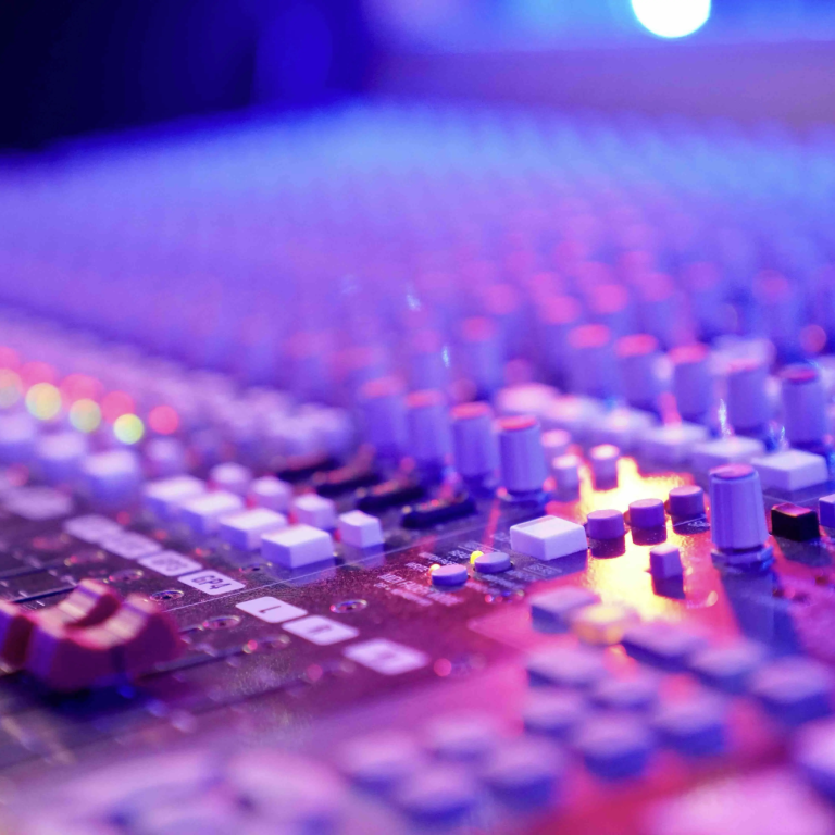 Album-Produktion in Hamburg Nahaufnahme eines Mischpults mit bunten Reglern und Lichtern.