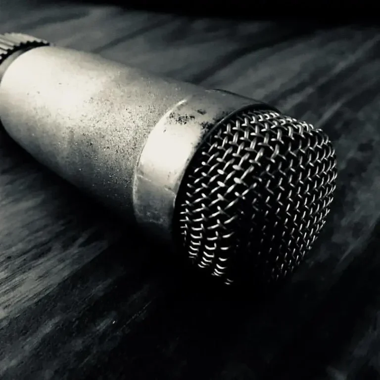 Audio-Restauration in Hamburg Nahaufnahme eines alten, metallischen Mikrofons auf einem Holzuntergrund.