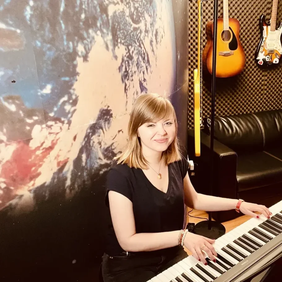 Tonaufnahmen Hamburg, Piano Frau spielt Klavier in einem modernen Musikstudio, lächelnd und konzentriert.