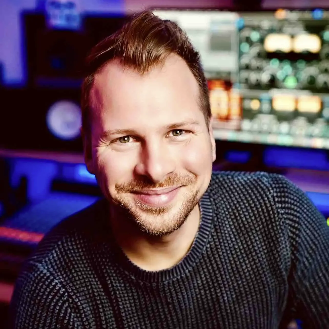 Timothy Spaniel, Musikproduzent, Audio Engineer Lächelnder Mann in einem Musikstudio, mit Mischpult im Hintergrund.